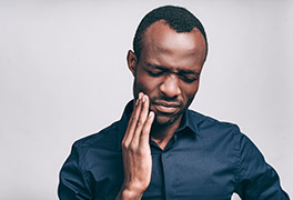 Man touching side of his face and grimacing in pain