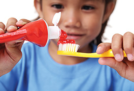 A child putting red toothpaste on a toothbrush