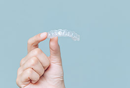 Hand holding up a clear orthodontic retainer