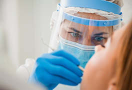 Dental professional wearing a mask and a face shield treating a patient